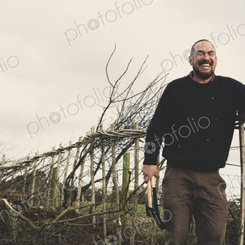 Bearded man holding axe and bill hook standing next to a newly built traditional… Bearded man holding axe and bill hook standing next to a newly built traditional…