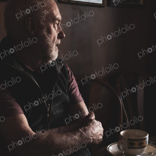 Bearded man sitting at a table with cup of coffee in a cafe.