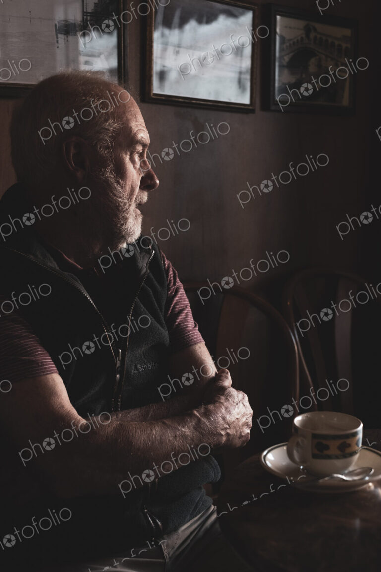 Bearded man sitting at a table with cup of coffee in a cafe.
