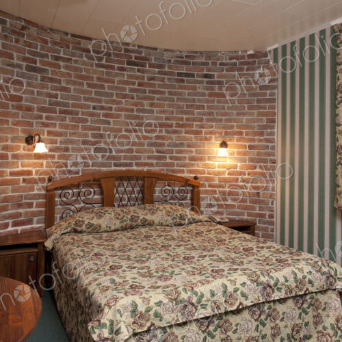 Bed in bedroom with wallpaper and brick wall. Bed in bedroom with wallpaper and brick wall.