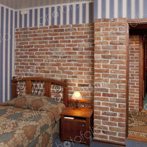 Bed in bedroom with wallpaper and brick wall. Bed in bedroom with wallpaper and brick wall.
