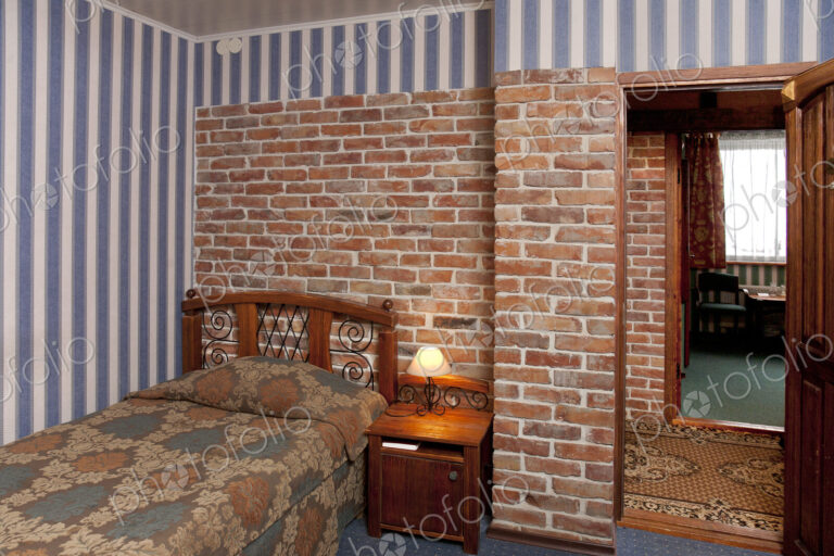 Bed in bedroom with wallpaper and brick wall.