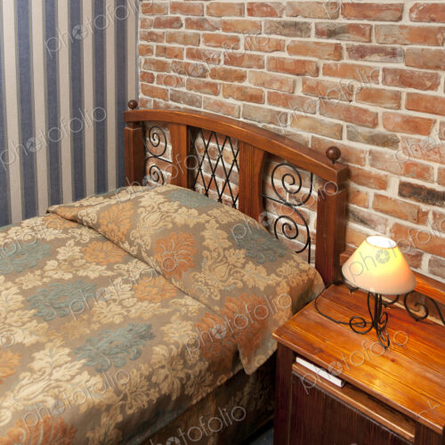 Bed in bedroom with wallpaper and brick wall. Bed in bedroom with wallpaper and brick wall.