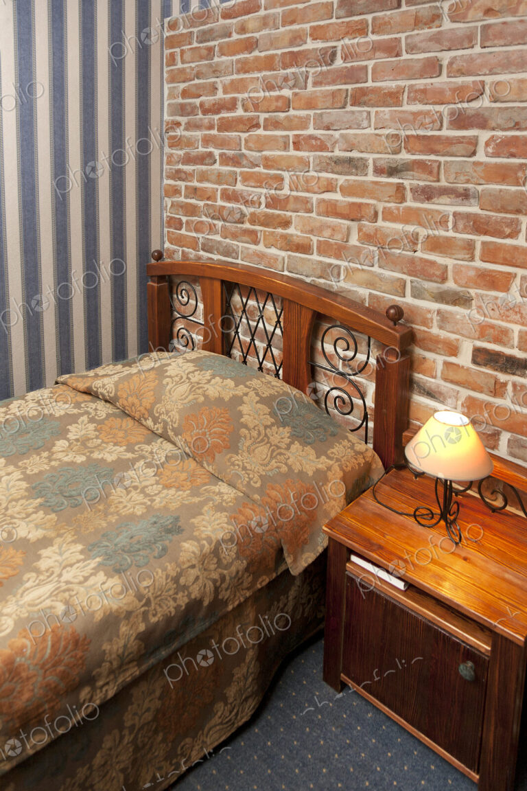 Bed in bedroom with wallpaper and brick wall.