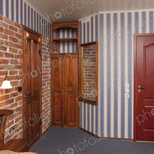 Bed in bedroom with wallpaper and brick wall and wooden cupboards and doors. Bed in bedroom with wallpaper and brick wall and wooden cupboards and doors.