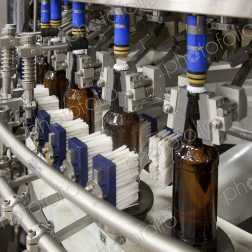 Beer bottling plant with moving belts, rows of bottles, automated process, capping and… Beer bottling plant with moving belts, rows of bottles, automated process, capping and…