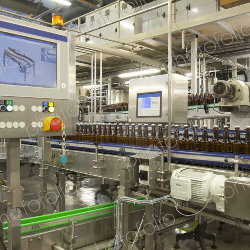 Beer bottling plant with moving belts, rows of bottles, automated process, capping and… Beer bottling plant with moving belts, rows of bottles, automated process, capping and…