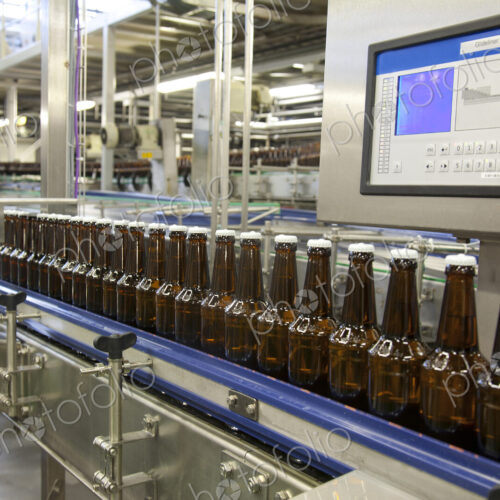 Beer bottling plant with moving belts, rows of bottles, automated process, capping and… Beer bottling plant with moving belts, rows of bottles, automated process, capping and…