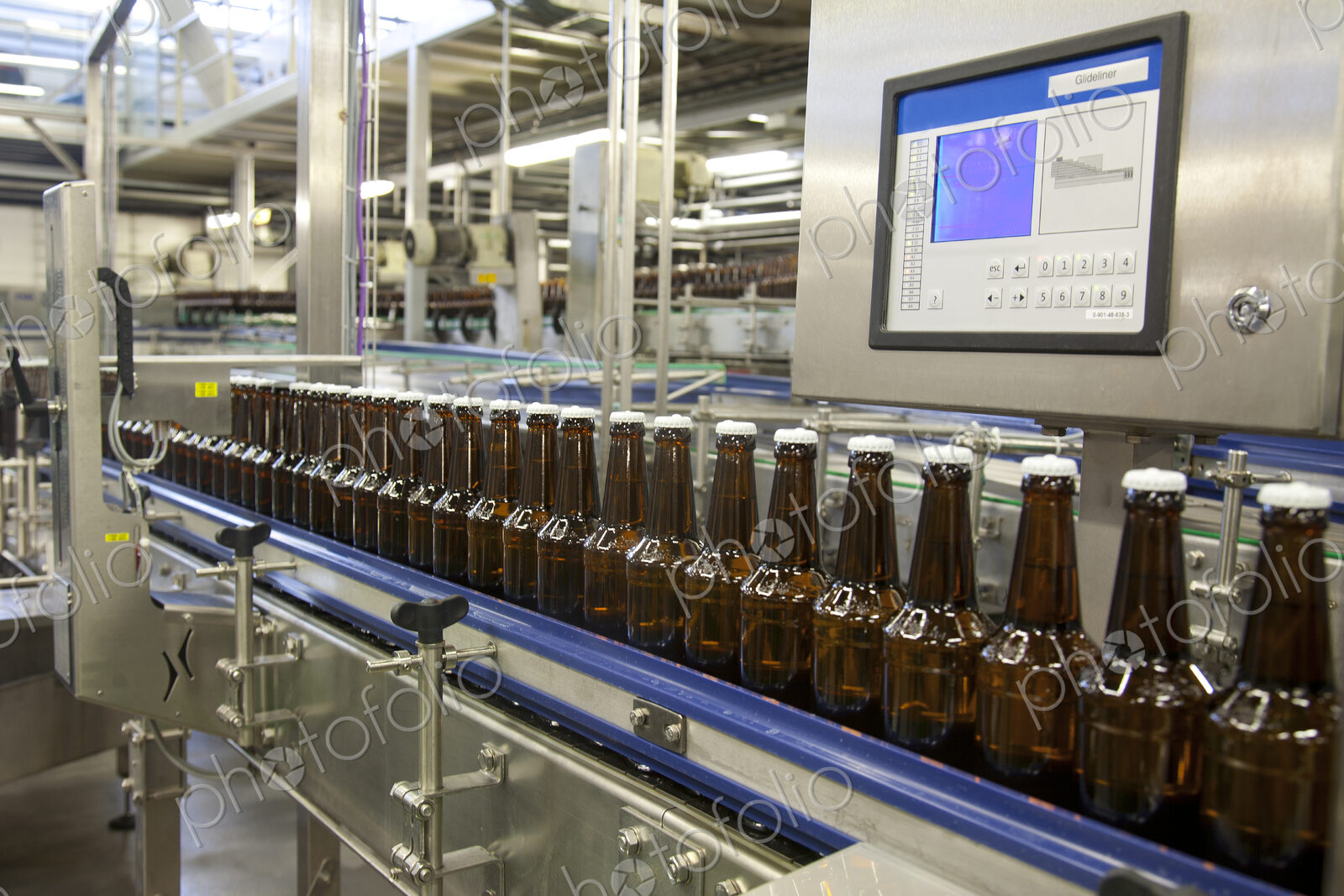 Beer bottling plant with moving belts, rows of bottles, automated process, capping and…