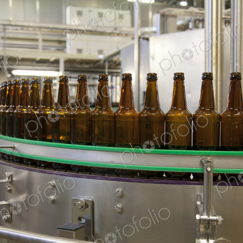 Beer bottling plant with moving belts, rows of bottles, automated process, capping and… Beer bottling plant with moving belts, rows of bottles, automated process, capping and…