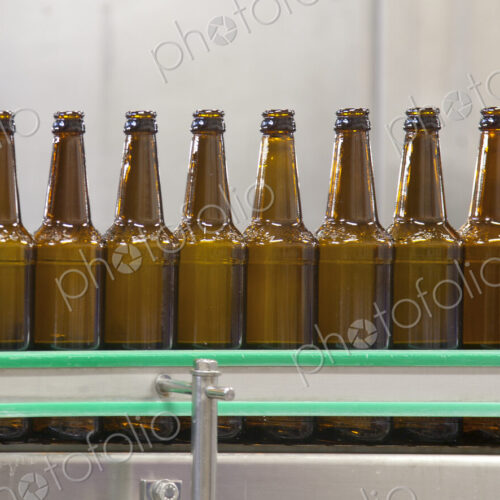 Beer bottling plant with moving belts, rows of bottles, automated process, capping and… Beer bottling plant with moving belts, rows of bottles, automated process, capping and…