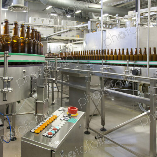 Beer bottling plant with moving belts, rows of bottles, automated process, capping and… Beer bottling plant with moving belts, rows of bottles, automated process, capping and…