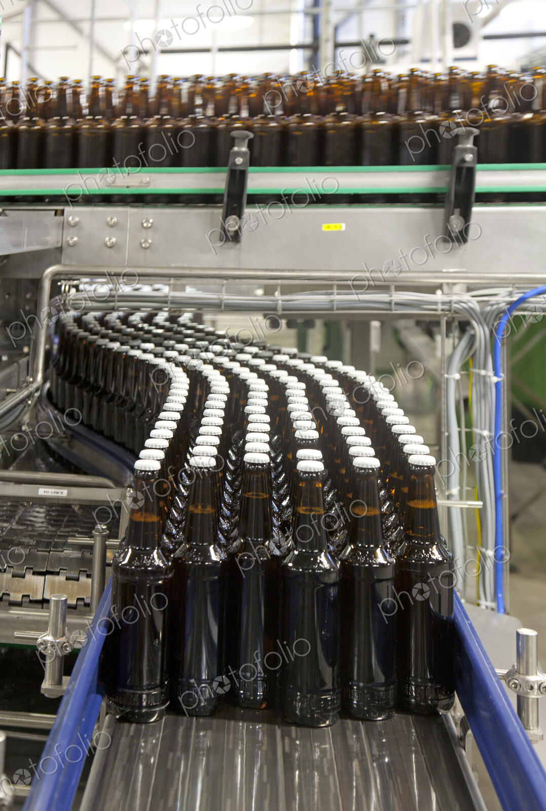 Beer bottling plant with moving belts, rows of bottles, automated process, capping and…