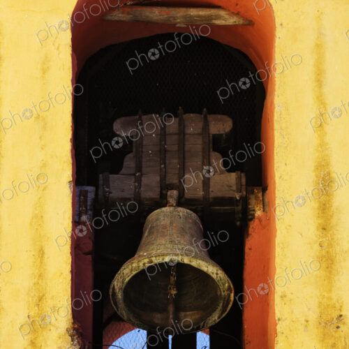 Bell tolling in a yellow painted arch.