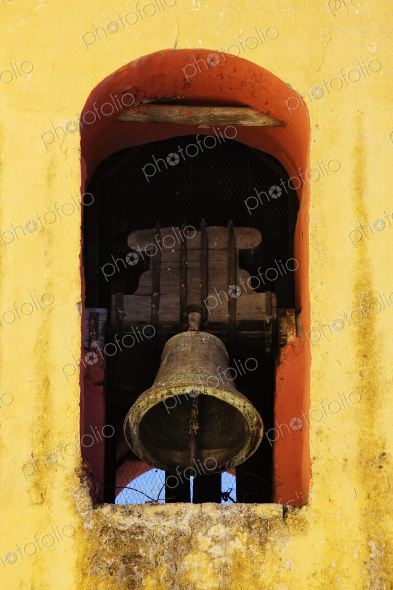 Bell tolling in a yellow painted arch.