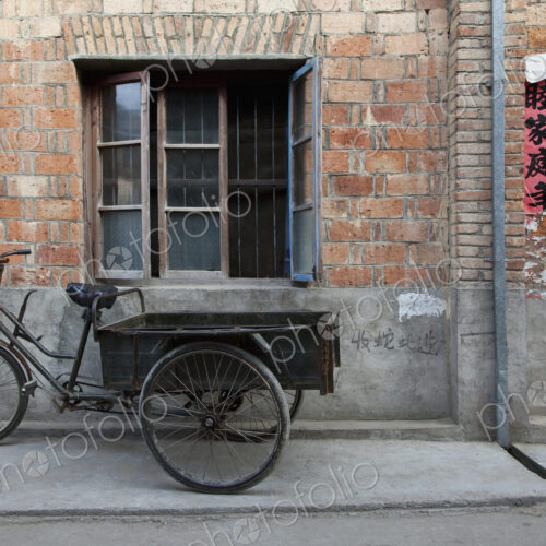 Bicycle and cart outside a small house on a street Bicycle and cart outside a small house on a street