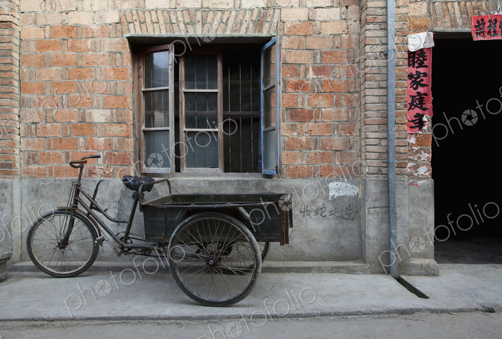 Bicycle and cart outside a small house on a street