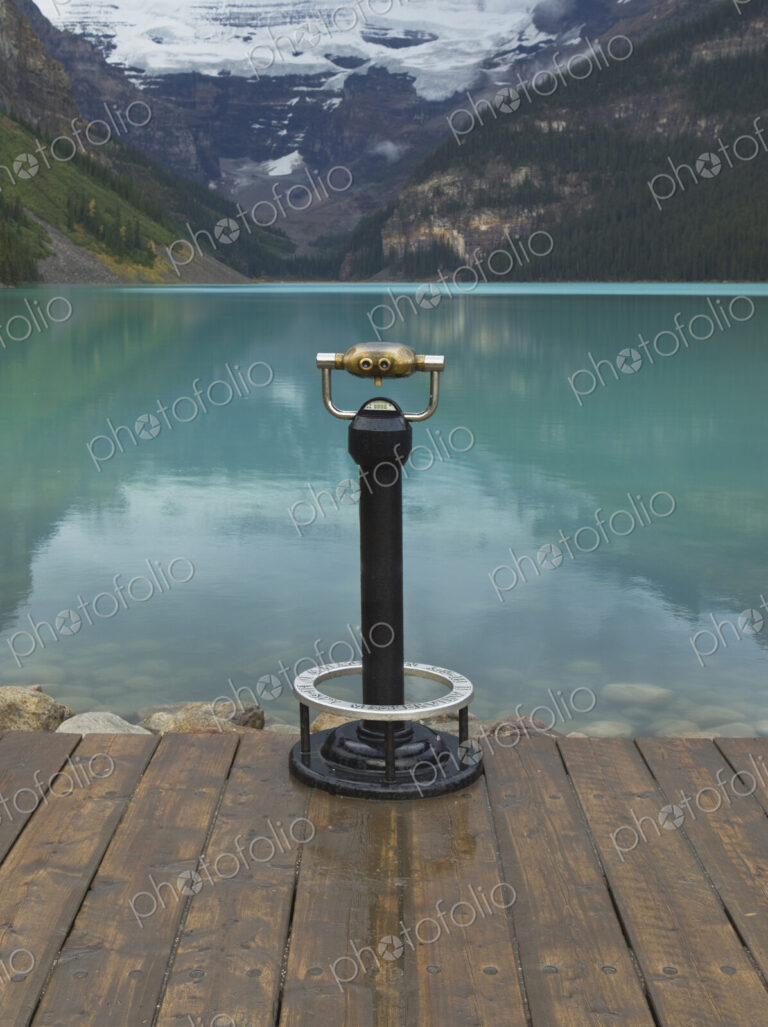 Binoculars overlooking still lake in rural landscape