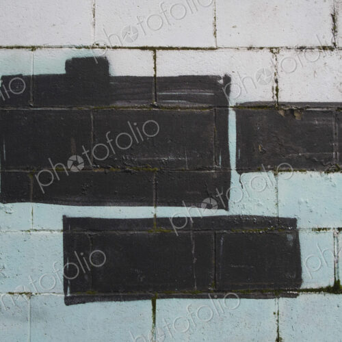 Black and green paint covering graffiti tags on building wall