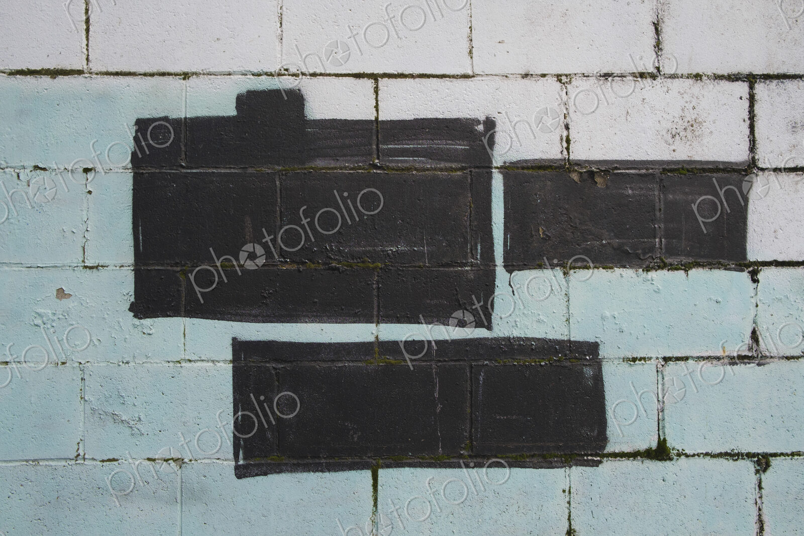 Black and green paint covering graffiti tags on building wall