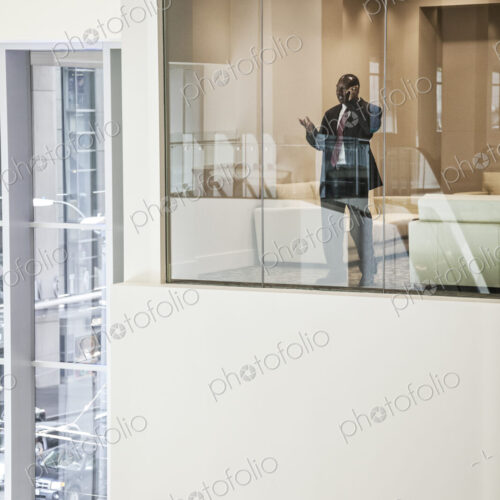 Black busiinessman on the phone standing in a conference room window. Black busiinessman on the phone standing in a conference room window.