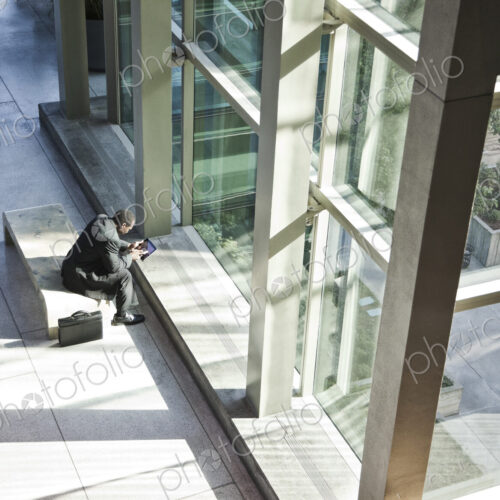 Black business man on a notebook computer sitting in a waiting area of a large open lobby. Black business man on a notebook computer sitting in a waiting area of a large open lobby.