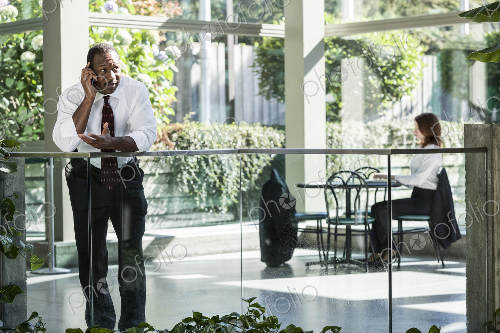 Black business man on the phone in a large open lobby waiting area.