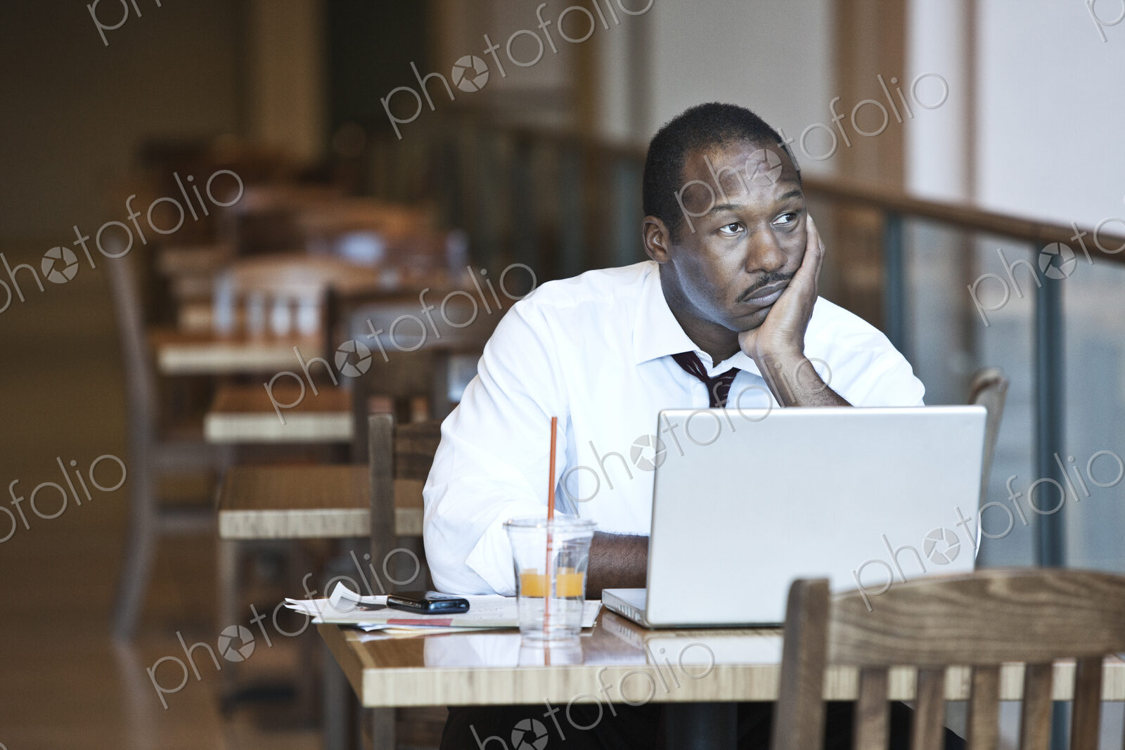 Black business man working on a lap top computer in a coffee shop.