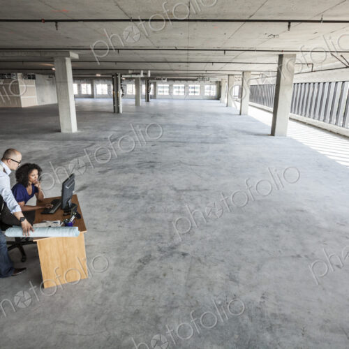 Black business woman and Asian business man working on a computer at a desk in a large…