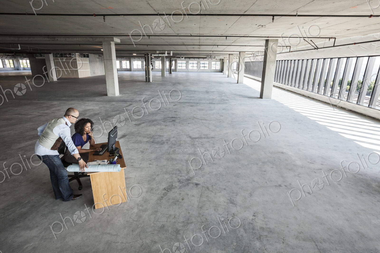 Black business woman and Asian business man working on a computer at a desk in a large…