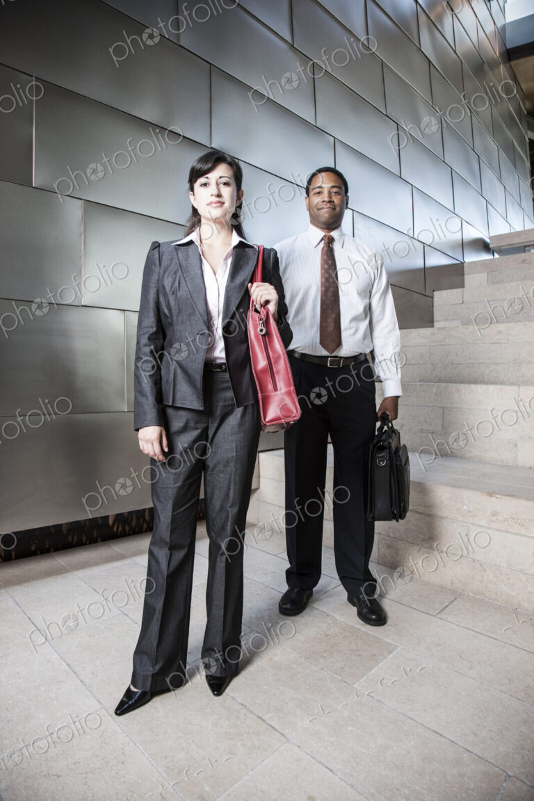 Black businessman and Hispanic businesswoman in the lobby of a large office building.
