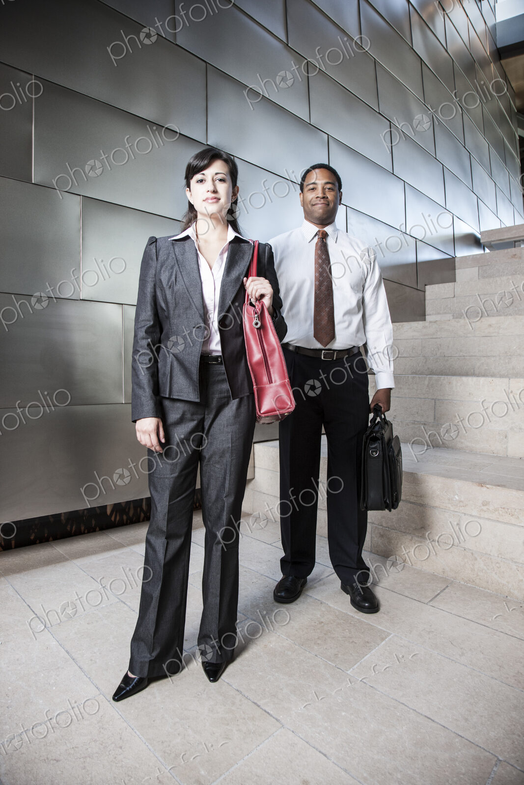 Black businessman and Hispanic businesswoman in the lobby of a large office building.