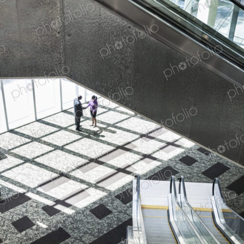 Black businessman and woman meeting in the lobby of a large business center. Black businessman and woman meeting in the lobby of a large business center.