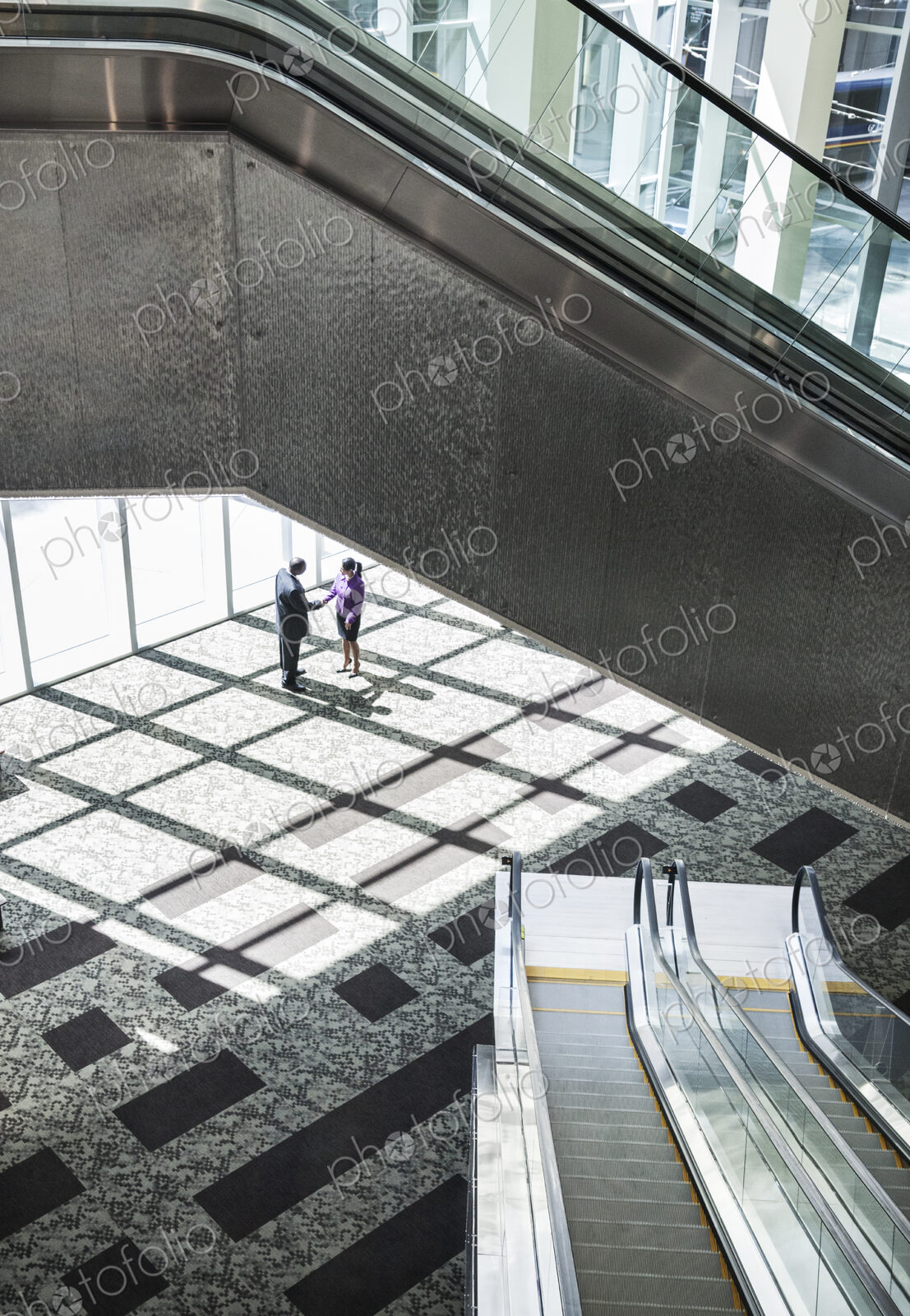 Black businessman and woman meeting in the lobby of a large business center.