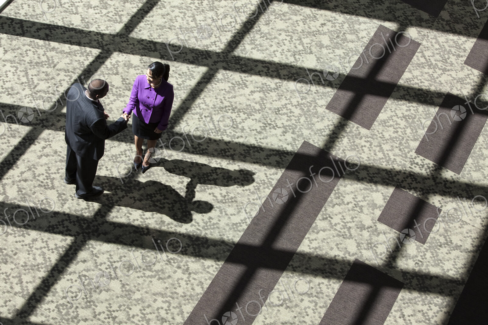 Black businessman and woman meeting in the lobby of a large business center.