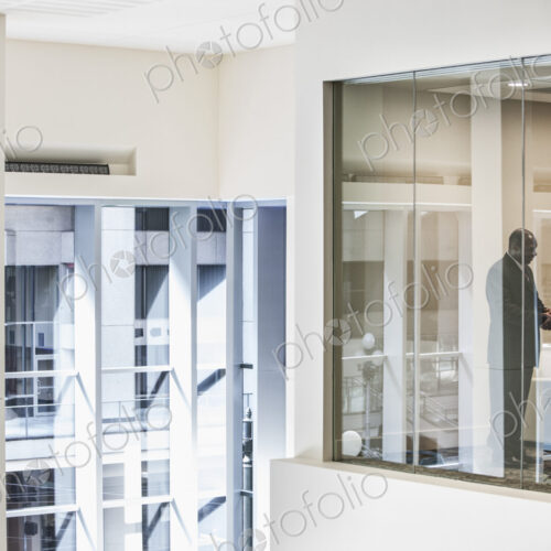 Black businessman and woman shaking hands in conference room window.