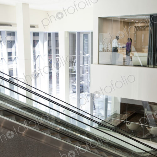 Black businessman and woman shaking hands in conference room window.