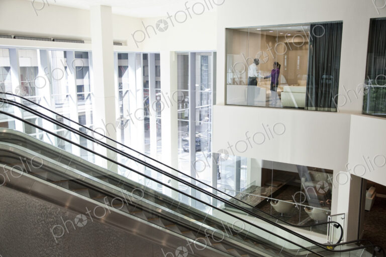Black businessman and woman shaking hands in conference room window.