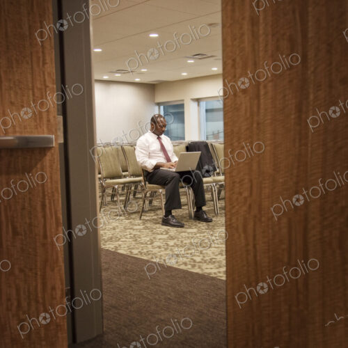 Black businessman in a conference center meeting space working on lap top. Black businessman in a conference center meeting space working on lap top.