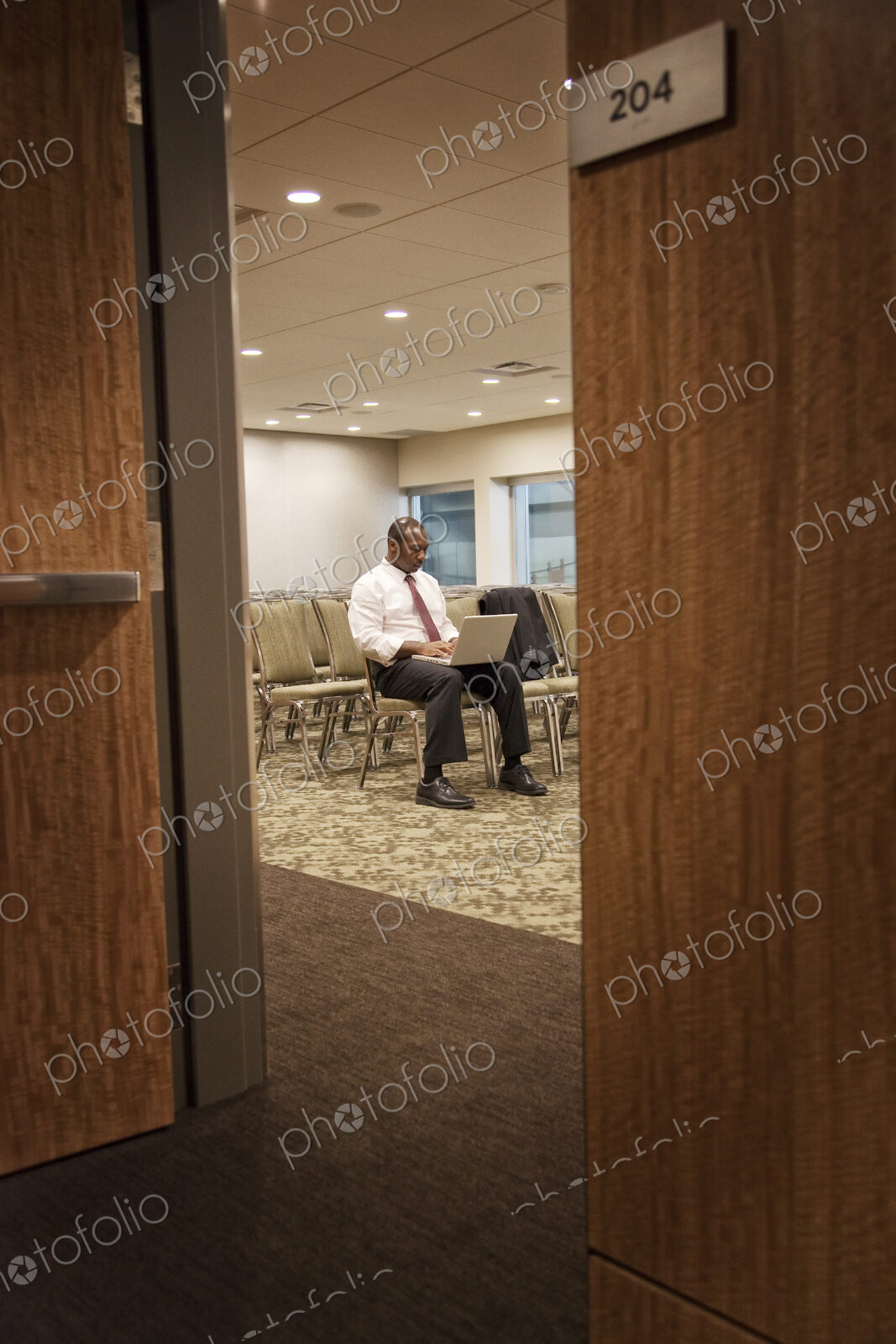 Black businessman in a conference center meeting space working on lap top.