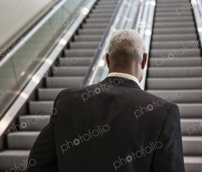 Black businessman on his way up an office escalator.