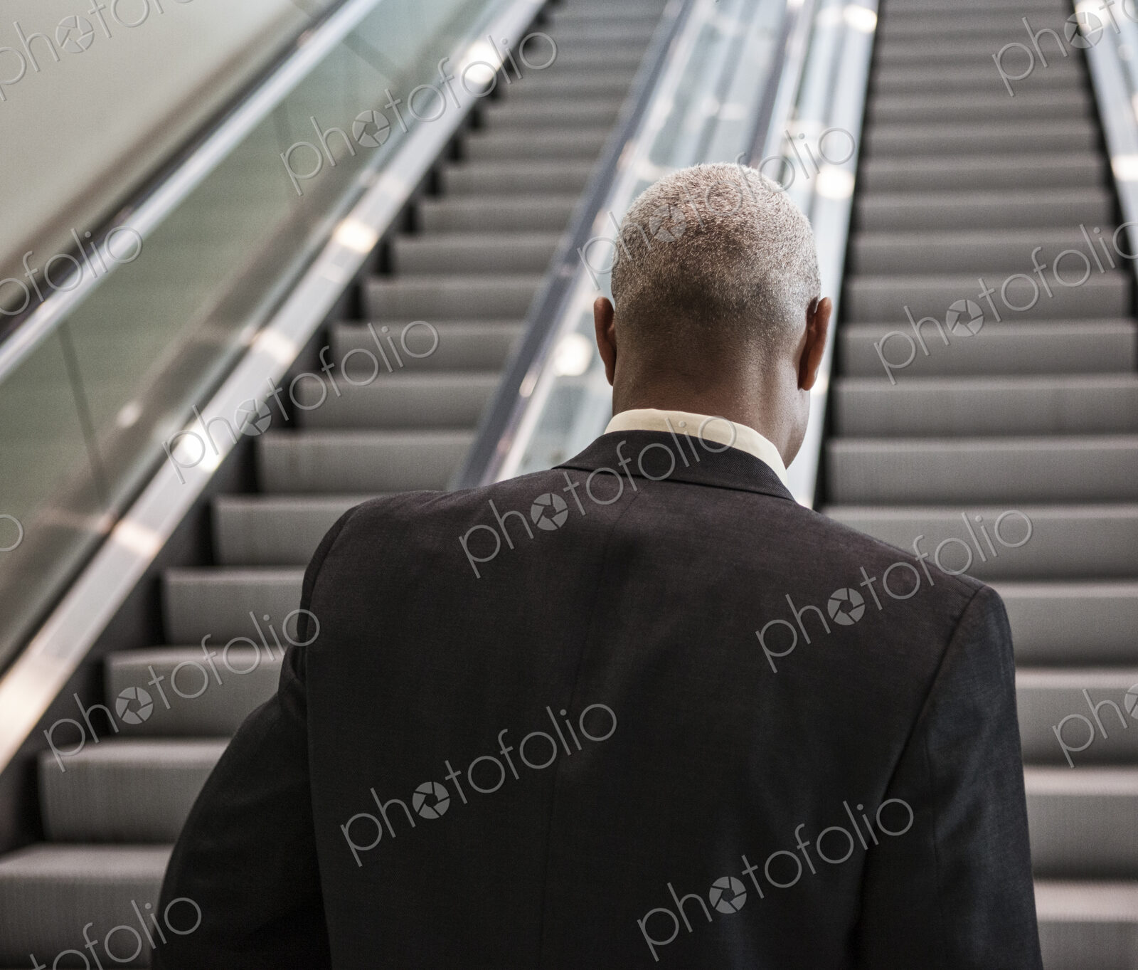 Black businessman on his way up an office escalator.