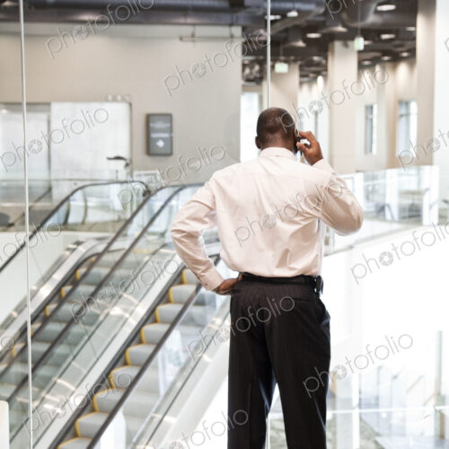 Black businessman on the phone in a large business center lobby.