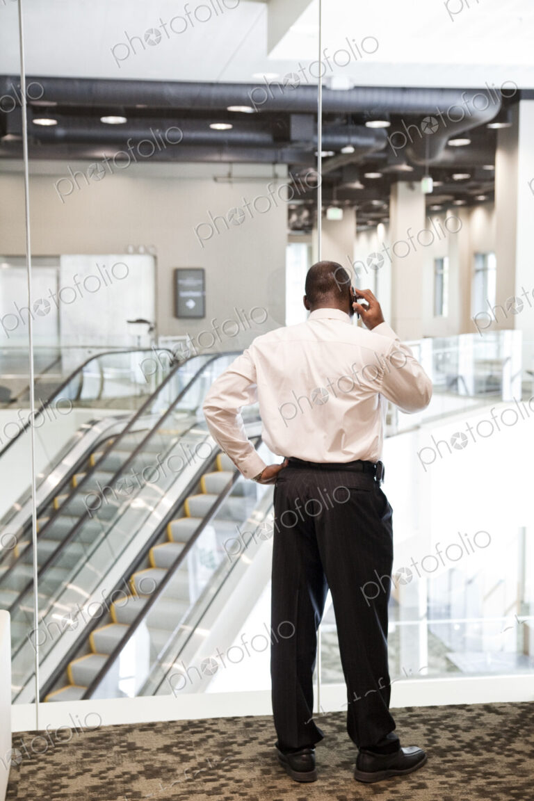 Black businessman on the phone in a large business center lobby.