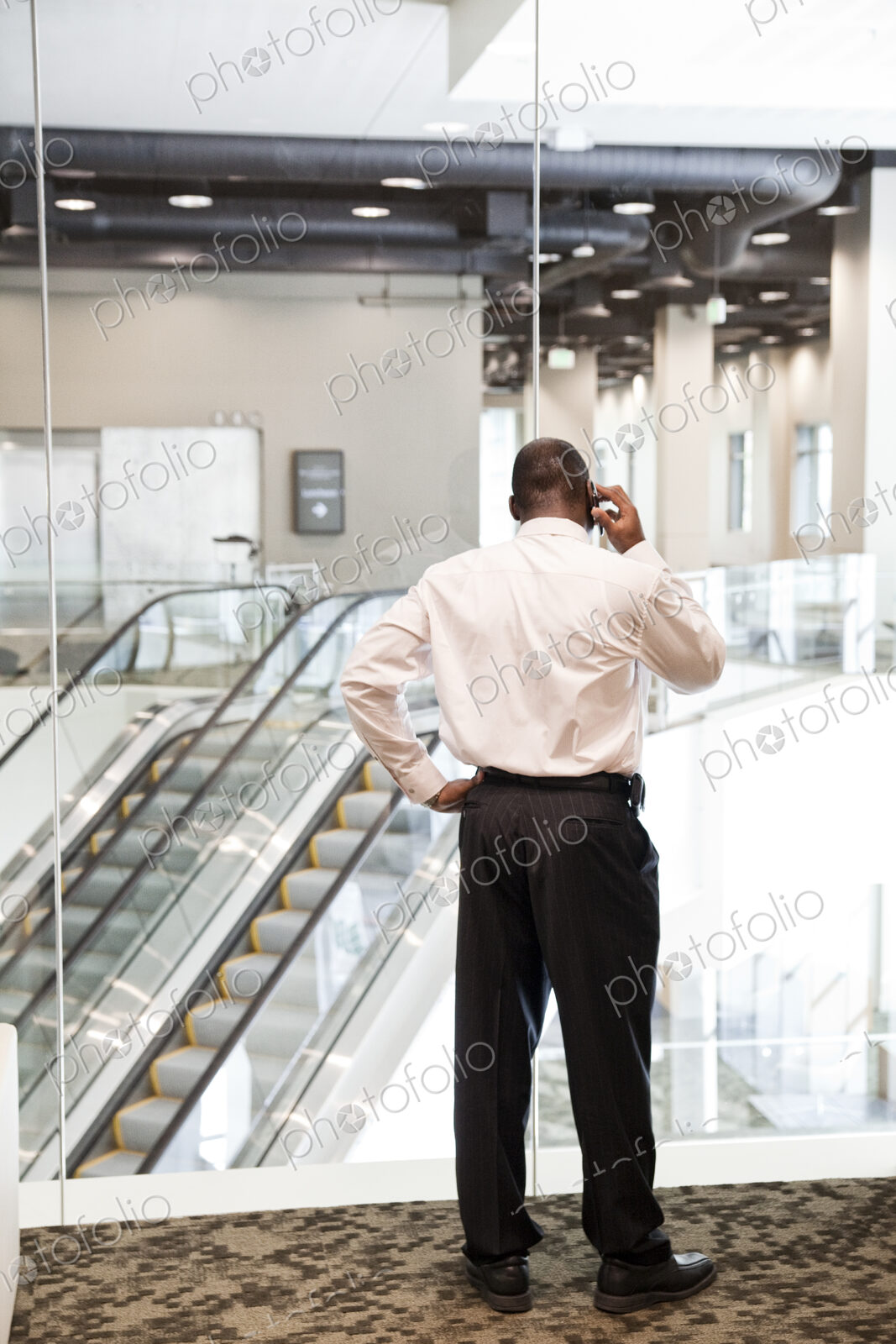 Black businessman on the phone in a large business center lobby.
