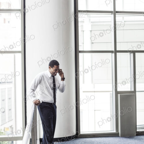 Black businessman on the phone in an office lobby.