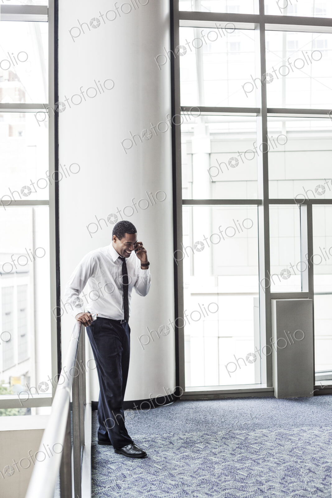Black businessman on the phone in an office lobby.