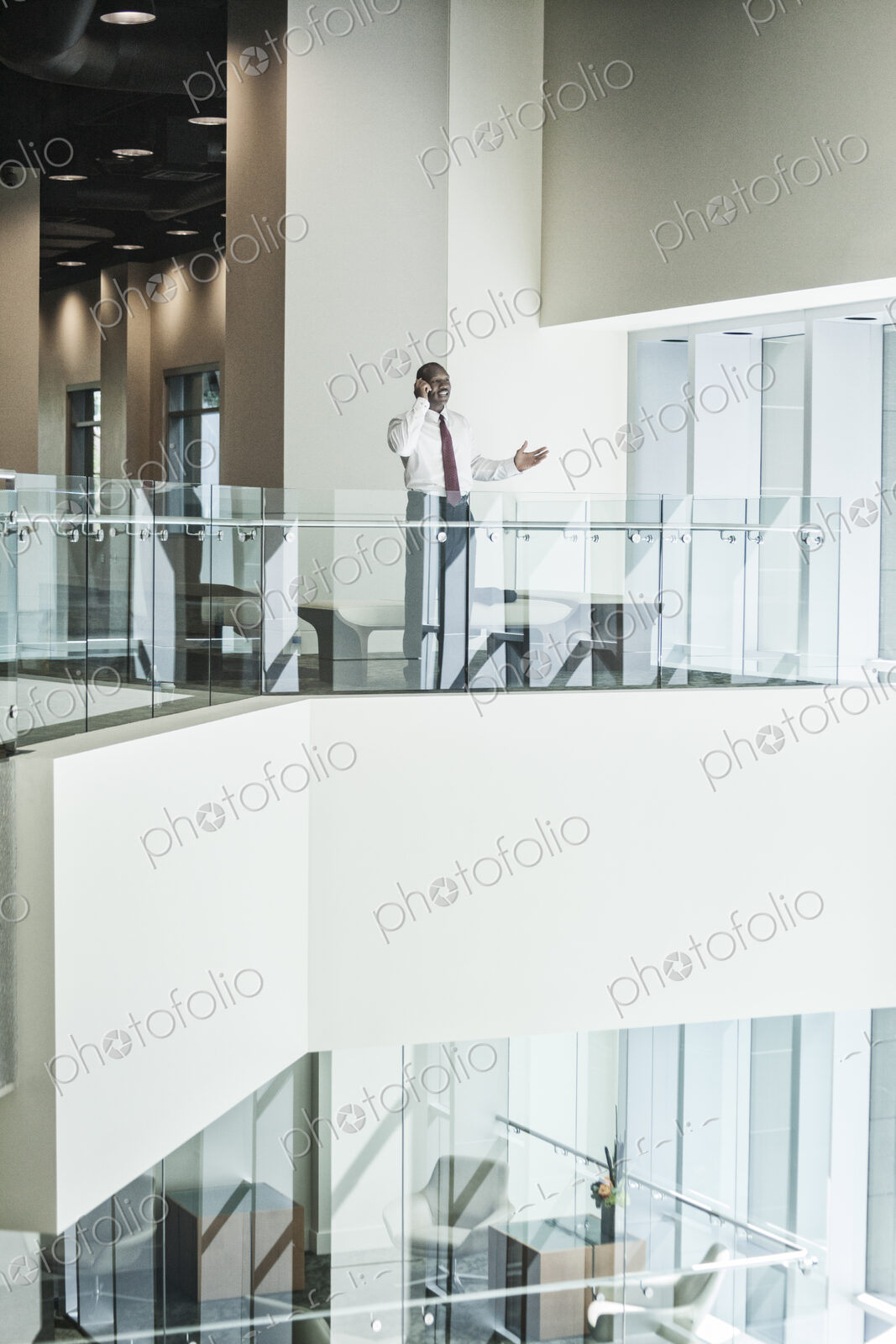 Black businessman on the phone standing in the lobby of a large business center.