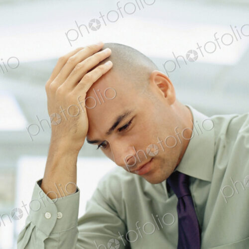 Black businessman rubbing his head