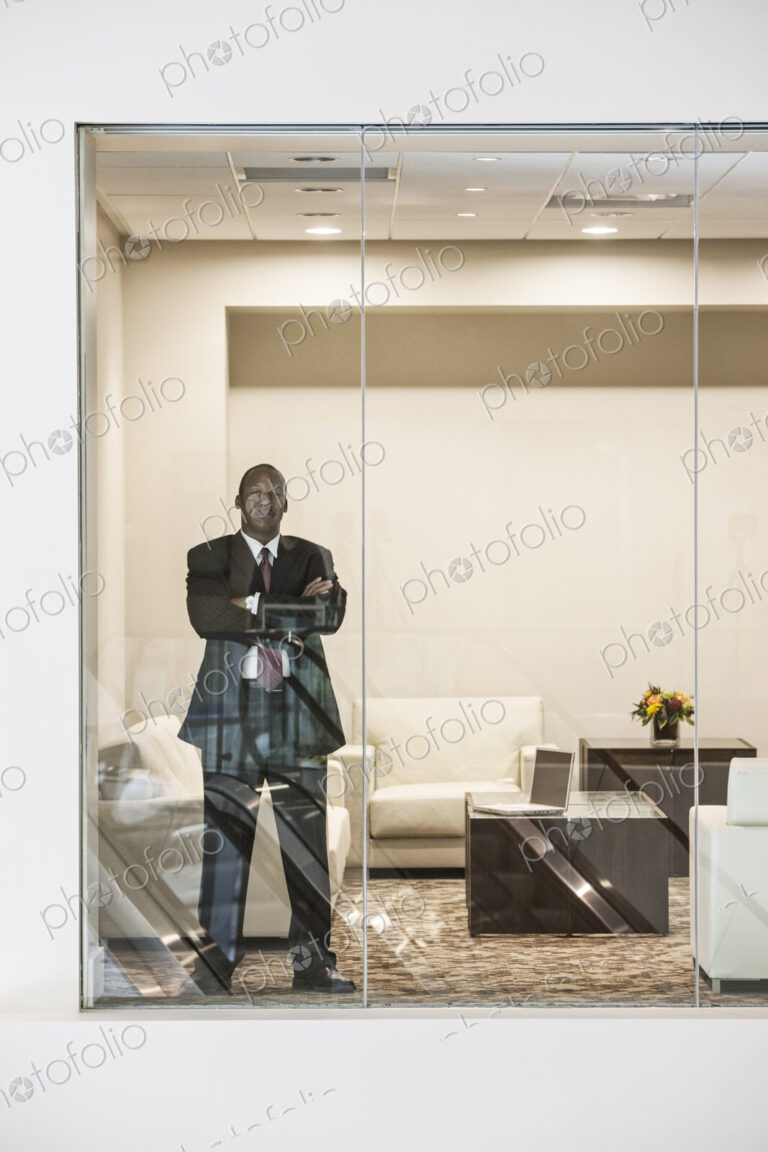 Black businessman standing in conference room window.